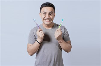 Smiling guy holding two toothbrushes isolated. Smiling people showing two toothbrushes isolated