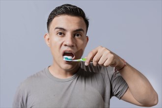 Handsome guy brushing his teeth isolated