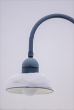 Snow-covered lamp of a public streetlight