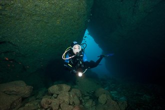 Diver dives through illuminated cave Underwater cave