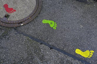 Colourful footprints on manhole covers and asphalt