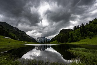Groeppelensee with reflection of the Altmann summit in the background under a threatening cloudy sky