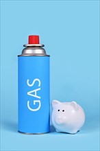 Gas cartridge bottle with piggy bank on blue background. Concept for saving gas