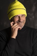 Older man with yellow winter cap smiles