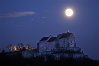 Illuminated Christmas tree on the unlit Burghausen Castle with full moon