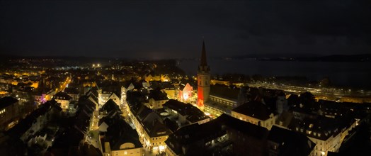 Aerial view of the town of Radolfzell on Lake Constance at night with the Minster Tower illuminated at Christmas