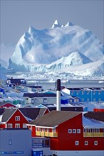 Chimney and different coloured houses in front of huge icebergs