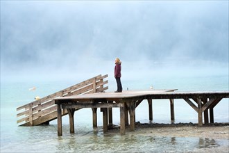 Woman on footbridge with fog am See