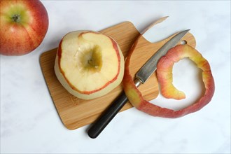 Peeled apple and apple peel with knife