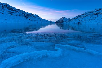 Ice structures in the black ice of the frozen Lago Bianco in the Swiss mountains in the evening light