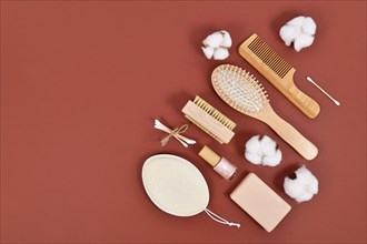 Eco friendly wooden beauty and hygiene products like comb and soap on brown background with copy space