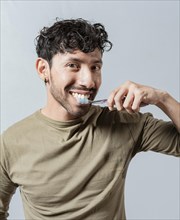 Smiling man brushing his teeth isolated