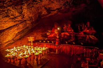 Cave with candles and Buddha images along the Kailash Kora