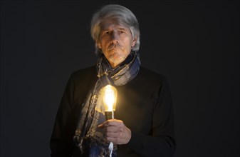 Elderly gentleman with scarf and luminous light bulb