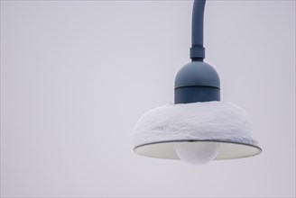 Snow-covered lamp of a public streetlight