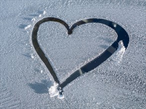 Heart painted on in fresh snow on frosty glass