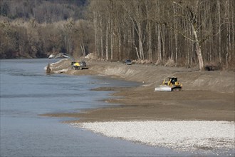 An excavator and a caterpillar reshape the banks of a river