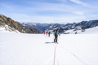 Ski tourers walking on the rope on the glacier