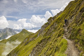 A hiker walks along the Gehrengrat on a steep slope. Lech