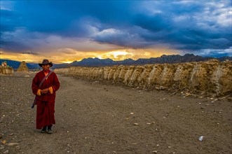 Monk walks along an eroded mud wall in the kingdom of Guge