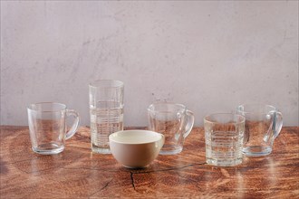 Empty glasses and cups of different forms and shapes on wooden tabletop