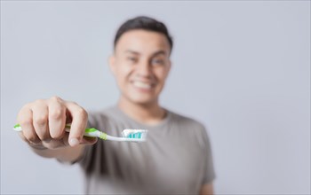 Smiling young man showing toothbrush with toothpaste isolated. Smiling people holding toothbrush with toothpaste with copy space