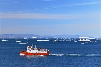 Red boat with tourists in front of icebergs