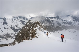Ski tourers walking on the rope on the glacier in winter in the mountains