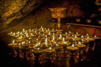 Cave with candles and Buddha images along the Kailash Kora