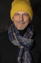 Older man with yellow winter cap smiles