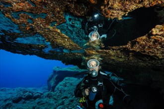Diver sees reflection underwater in air bubble in cave ceiling in entrance of underwater cave