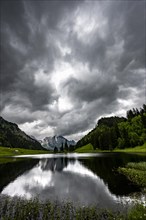 Groeppelensee with reflection of the Altmann summit in the background under a threatening cloudy sky