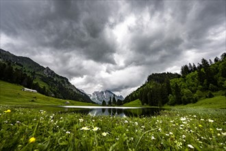 Groeppelensee with reflection of the Altmann summit in the background under a threatening cloudy sky