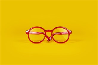 Small red round eye glasses on yellow background