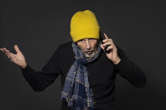 Elderly man with yellow winter cap excitedly talking on the phone