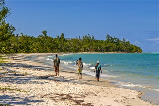 Workers walking on a long white sand beach in the east of the island Ile Sainte-Marie although Nosy Boraha
