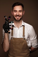 Manicur master man in working form with bottles of nail polish in hand. Nail photo content