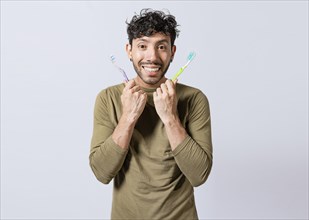 Handsome man holding two toothbrushes isolated. Smiling guy holding two toothbrushes isolated. Smiling people showing two toothbrushes isolated