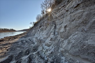 Steep wall of sand and dredge marks on a river bank