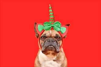 French Bulldog dog with Christmas unicorn headband in front of red background