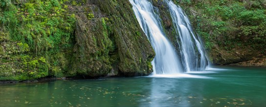 Waterfall from the source of the Lison in a haven of tranquillity with its waterfall surrounded by woods. Banner. Nans-sous-Sainte-Anne