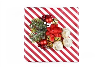 Christmas gift box with red and white striped wrapping paper and seasonal decoration isolated on white background