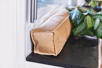 Draft excluder lying on window still to keep out cold air and save energy for heating in room