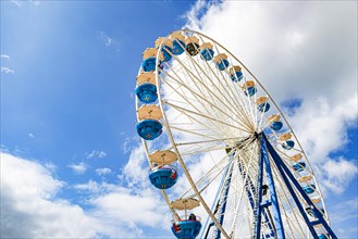 A Ferris wheel carousel soars into the summer sky