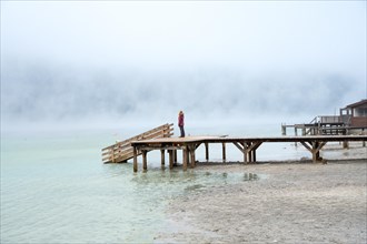 Woman on footbridge with fog am See