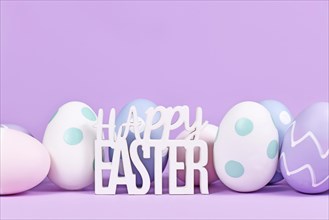 Easter eggs and text 'Happy Easter' on pastel violet background with copy space