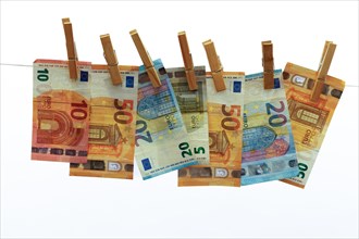 Euro banknotes hung on a clothesline with clothespins white background for copy space