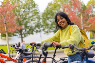 Portrait of smiling Asian female student parking bicycle at college campus