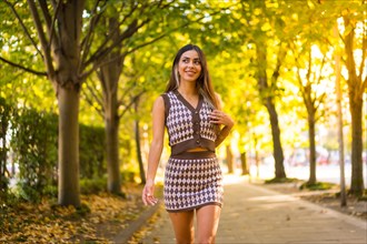 A caucasian brunette woman in autumn walking through a natural park in the city