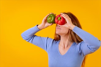 Vegetarian woman with spyglasses of peppers on her eyes on a yellow background